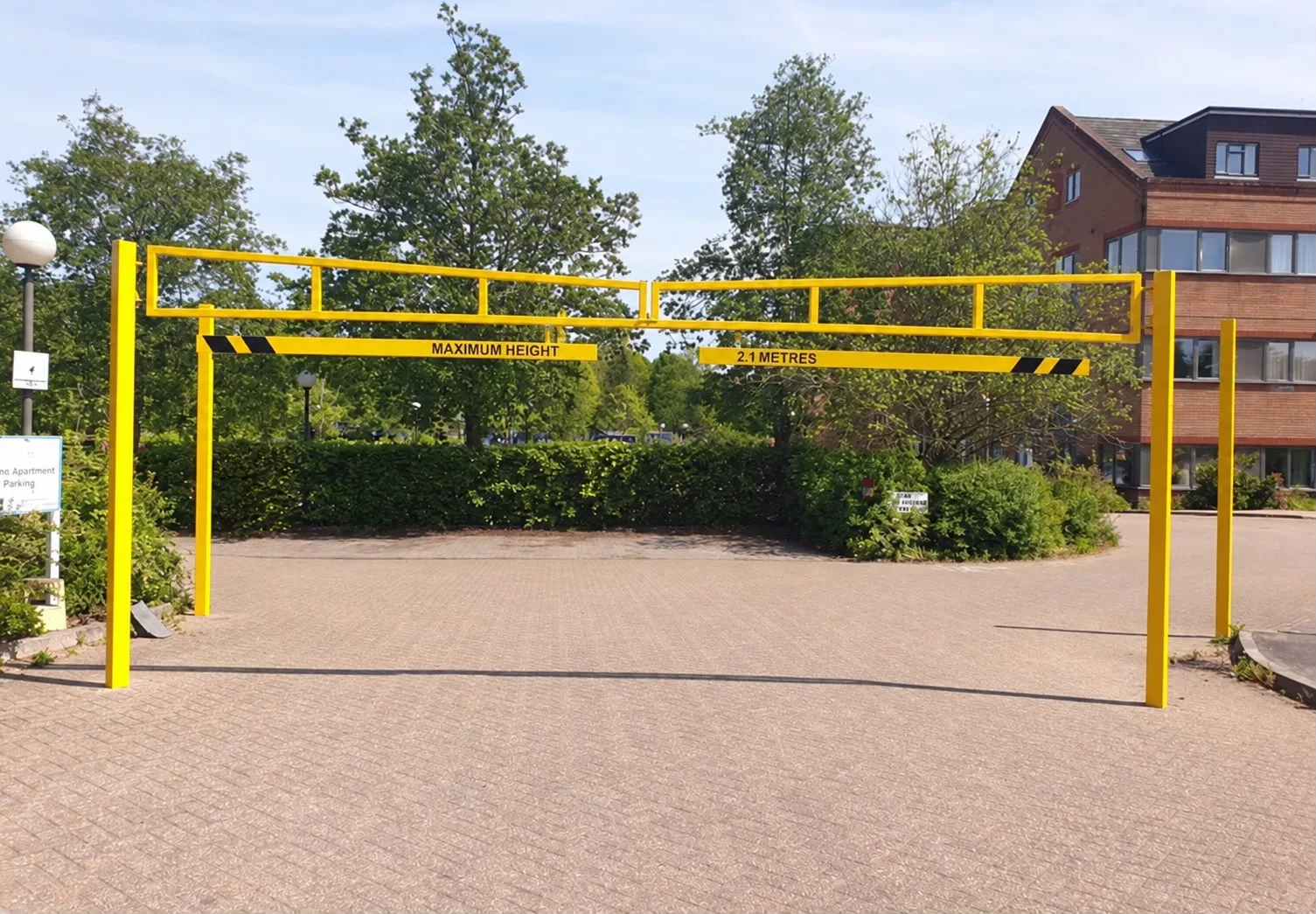 Yellow height restriction barrier across a block paved entrance